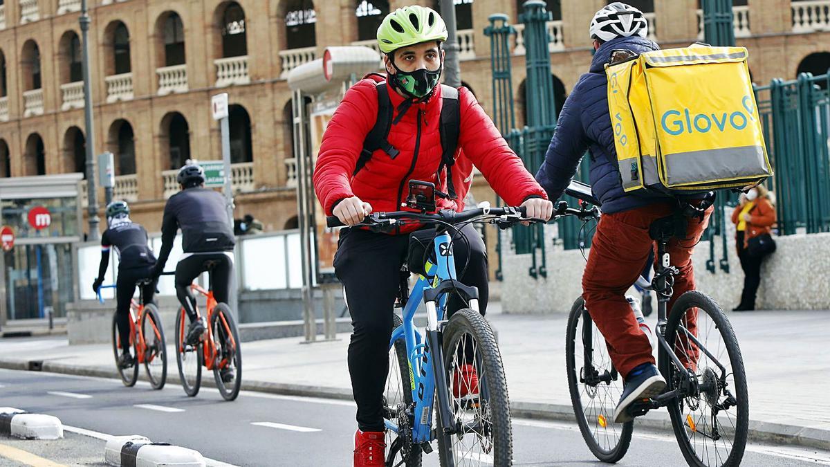 Dos «riders» pasan con sus bicicletas ante la plaza de toros de València, ayer a mediodía. | M. Á. MONTESINOS