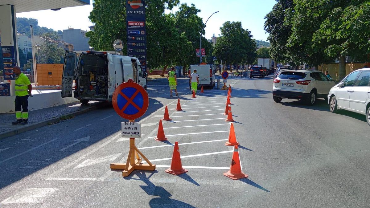 Brigades davant de la gasolinera pintant l'espai per a motots on abans hi aparcaven cotxes.