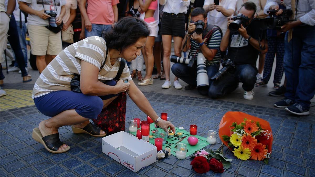 Una mujer deposita una vela sobre un cartel en el que puede leerse: Catalunya, lloc de pau, en la Rambla.