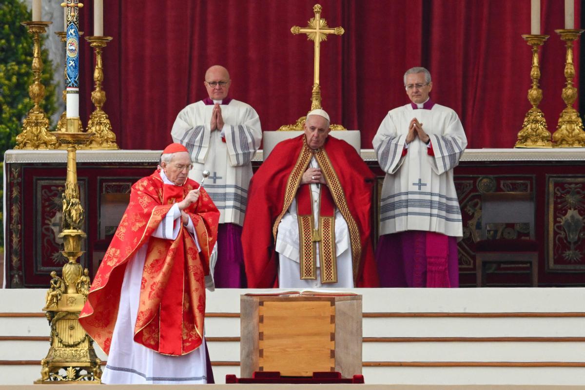 El cardenal italiano Giovanni Battista Re (L) bendice el ataúd del Papa emérito Benedicto XVI, mientras el Papa Francisco observa (C) durante su misa fúnebre en la plaza de San Pedro.