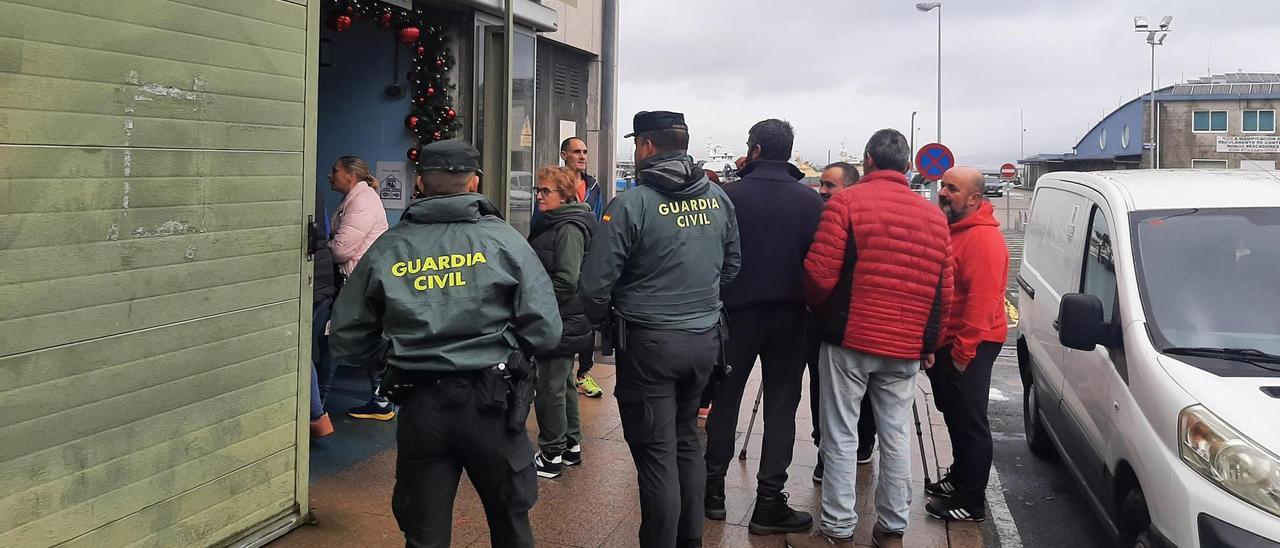 La Guardia Civil, vendedoras y marineros, ayer, en el acceso por el que entraron los ladrones.