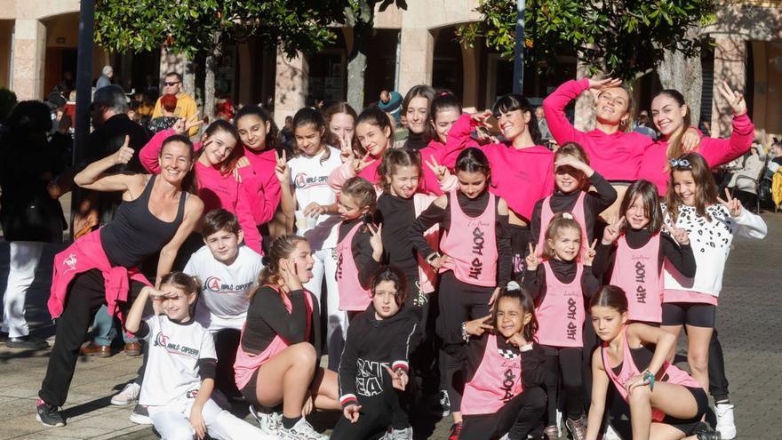 A la izquierda, participantes en la demostración de baile. Sobre estas líneas, vecinas recogen el bollo y la botella de sidra. | Mara Villamuza