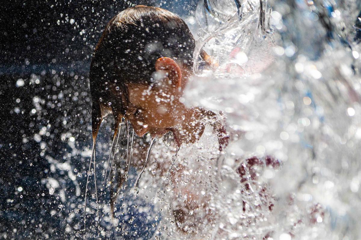 Un chico se refresca en una fuente en un parque de Washington DC.