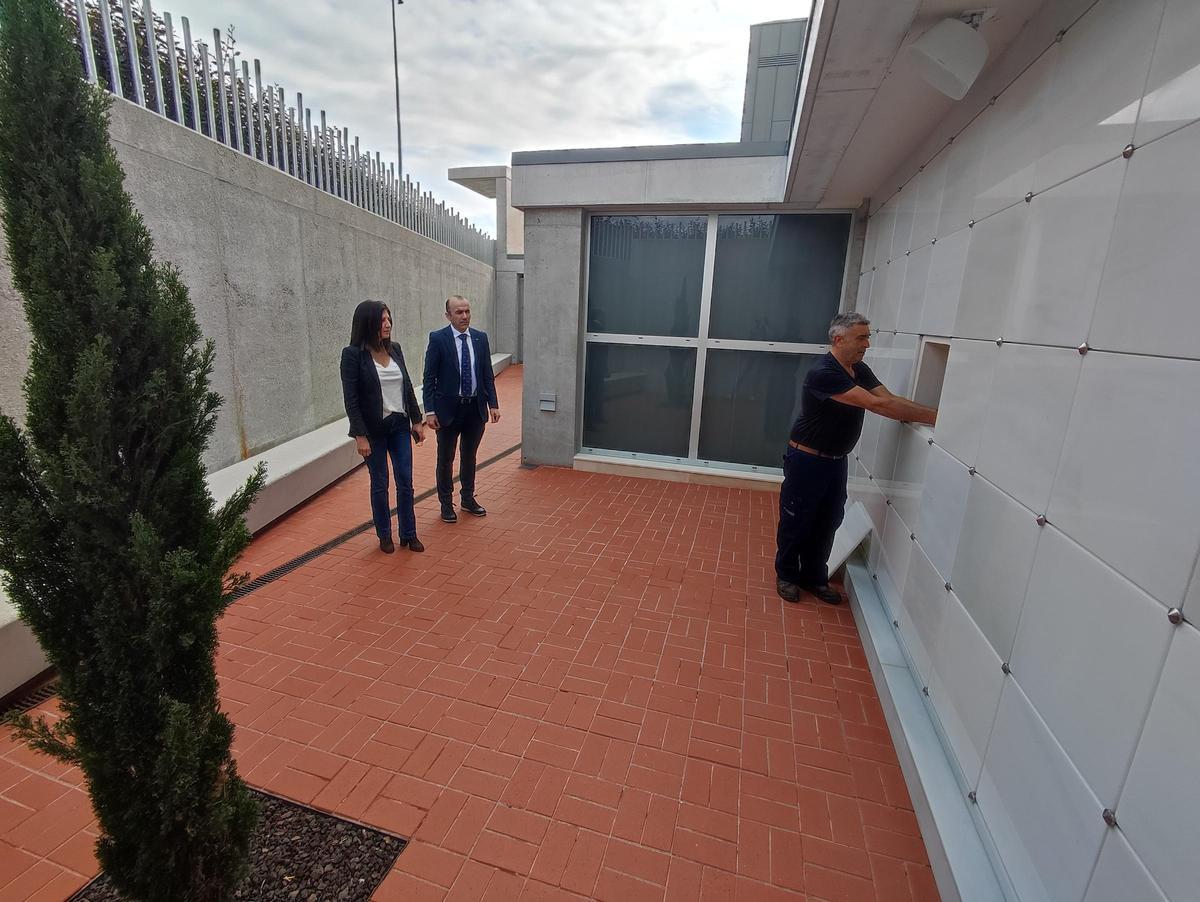 El trabajador Raimundo Méndez introduce una urna con cenizas en el columbario, en presencia de Daniel Iglesias y Marita García.