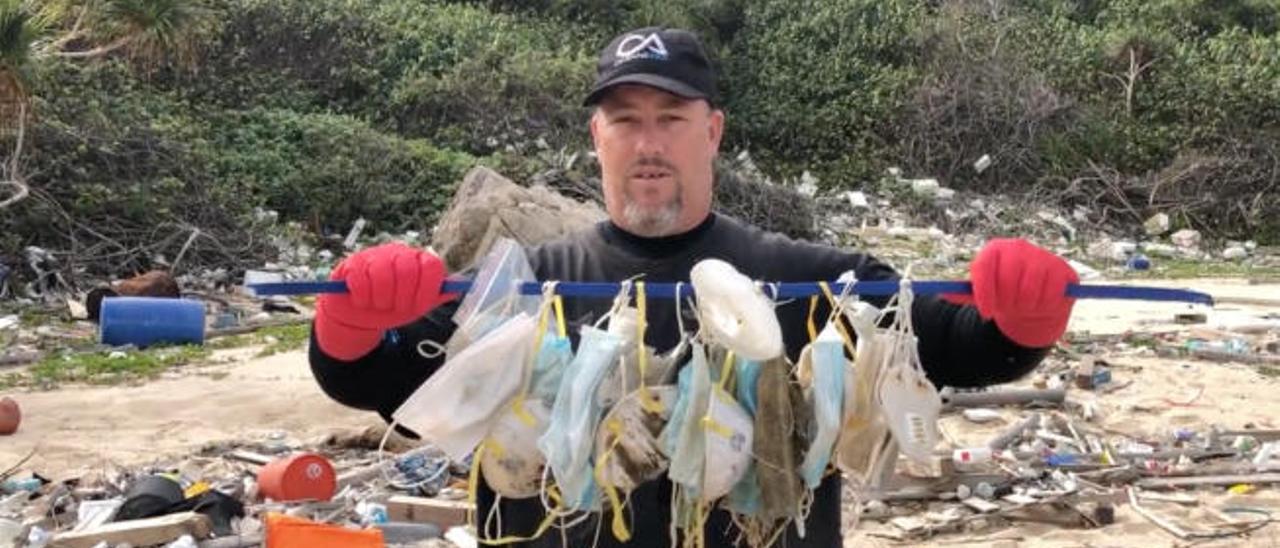 El ambientalista Gary Stokes con un matojo de mascarillas en Islas Soko, Hong Kong.