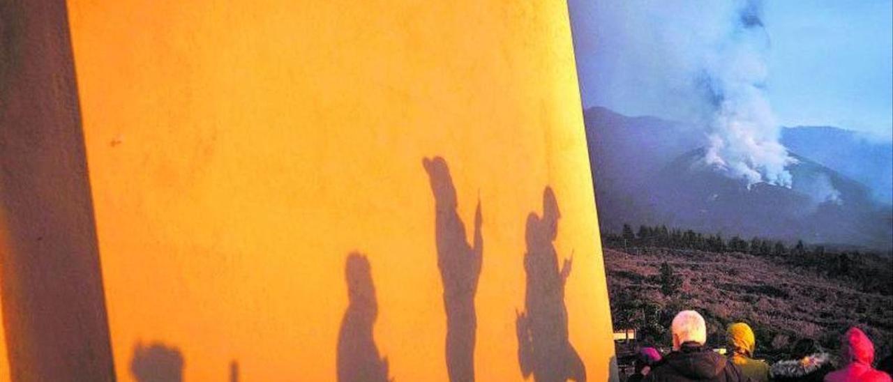 Un grupo de turistas observa el volcán desde Los Llanos de Aridane.