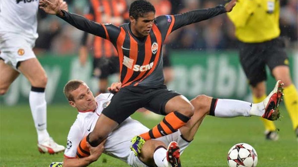 Douglas Costa junto a Nemanja Vidic (abajo) durante un Shakhtar-M. United de la Champions 2013-14