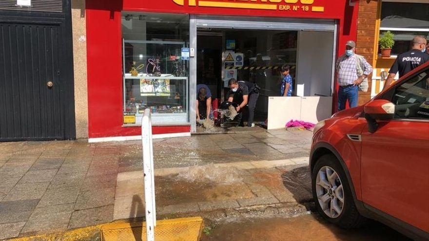 Álvaro Cumbres achica agua de su estanco ayudado por un agente de la Policía Local de Badajoz.