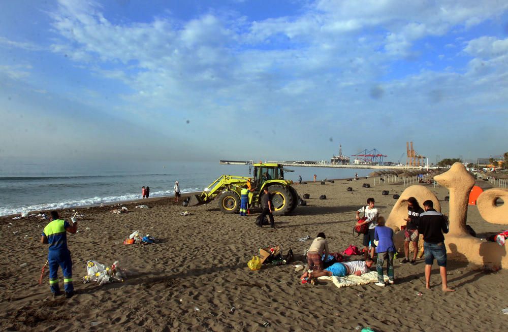 Los operarios de los servicios de limpieza trabajan para dejar la playa en óptimas condiciones tras una larga noche de fiesta en la arena