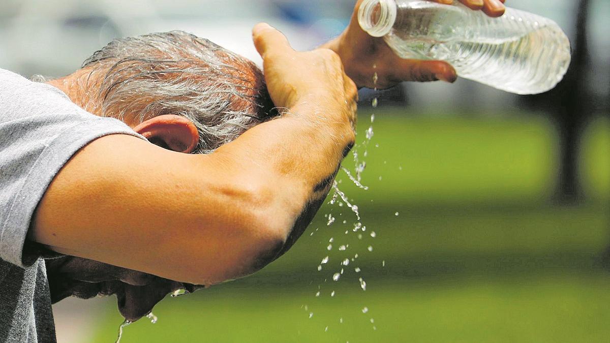 Un hombre refrescándose con una botella de agua