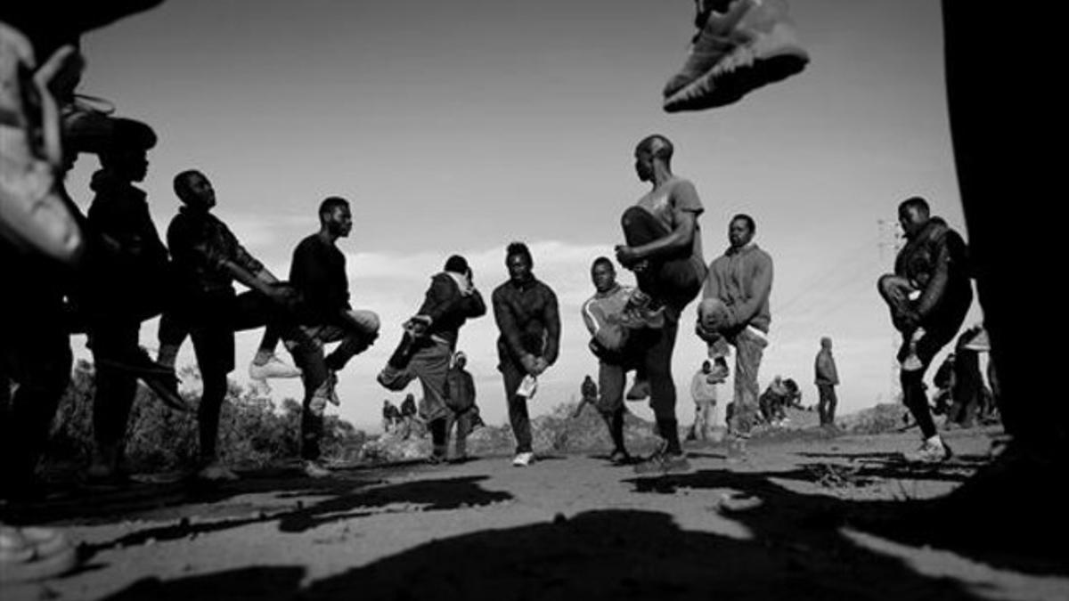 Inmigrantes de Mali y Camerún  calientan para jugar a fútbol en el monte Gurugú a la espera de saltar la valla.