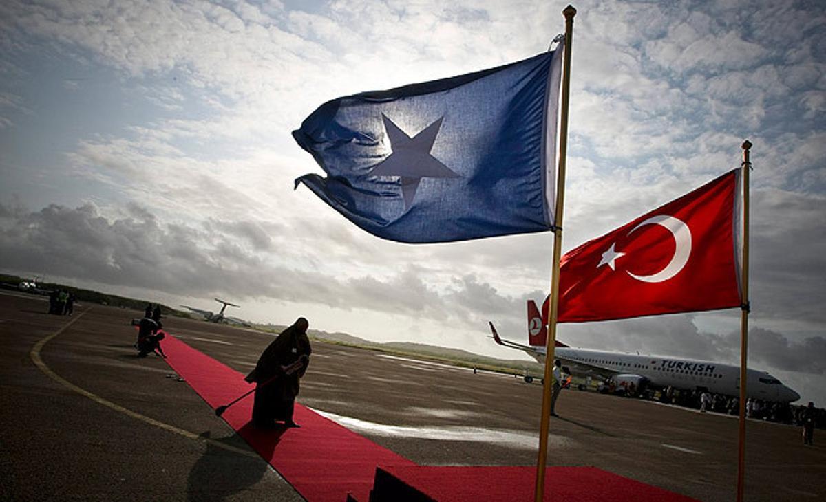 Una dona somali escombra l’alfombra vermella per on passarà el primer ministre turc, Tayip Erdogan, quan arribi a l’aeroport internacional de Mogadiscio.