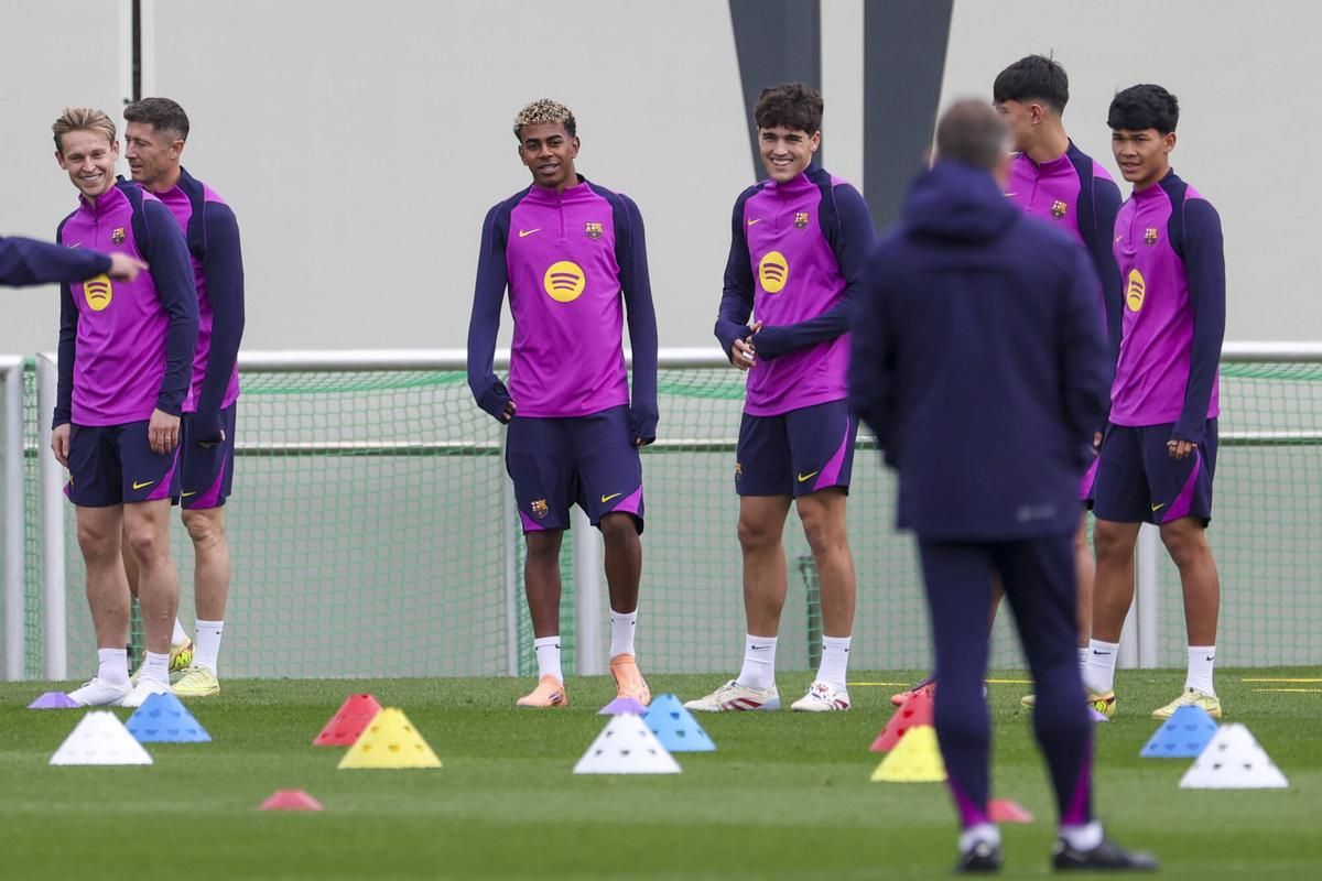 De Jong, Lamine Yamal y Cubarssí sonríen al escuchar a Hansi Flick, de espaldas.