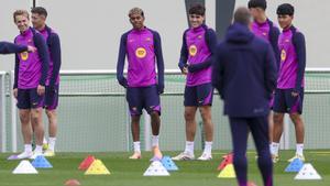 De Jong, Lamine Yamal y Cubarssí sonríen al escuchar a Hansi Flick, de espaldas.