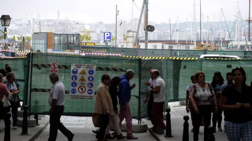 Peatones a su paso por el acceso a la plaza de María Pita desde Puerta Real, con las vallas al fondo.