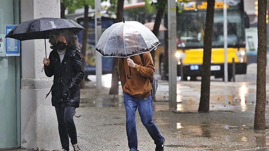 Vianants protegint-se de la pluja i el vent, ahir, a Girona.  | ANIOL RESCLOSA