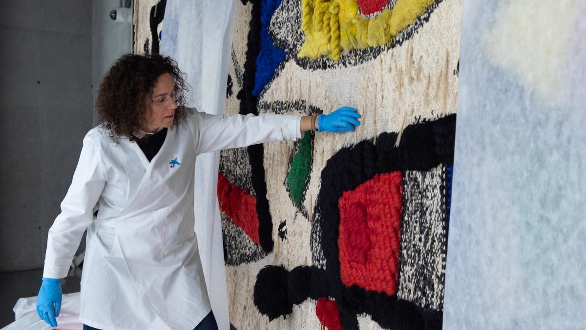 Una técnica participa en la colocación del tapiz que Joan Miró y el artista textil Josep Royo crearon para la Caixa en 1980, en CaixaForum Madrid, a 13 de enero de 2023, en Madrid (España).