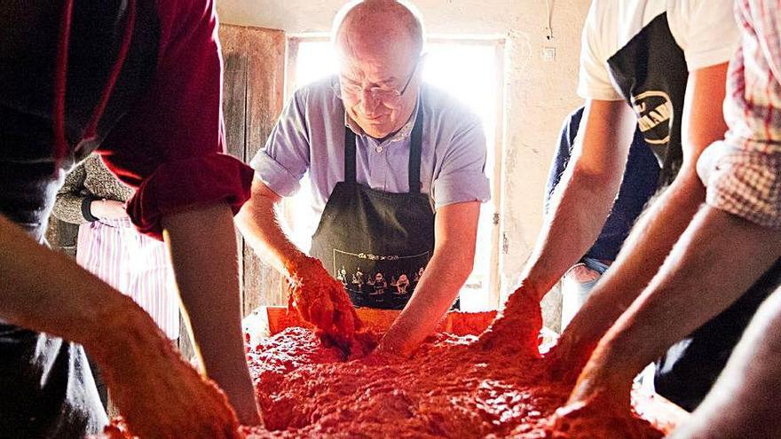 Varios hombres amasan la carne para hacer sobrasada.