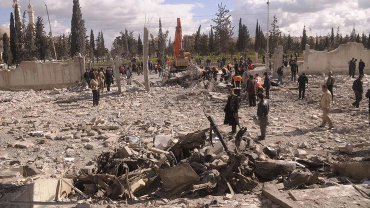 Agentes sirios inspeccionan la zona en la que ha estallado una bomba contra un edificio oficial, este viernes, en la ciudad de Aleppo.