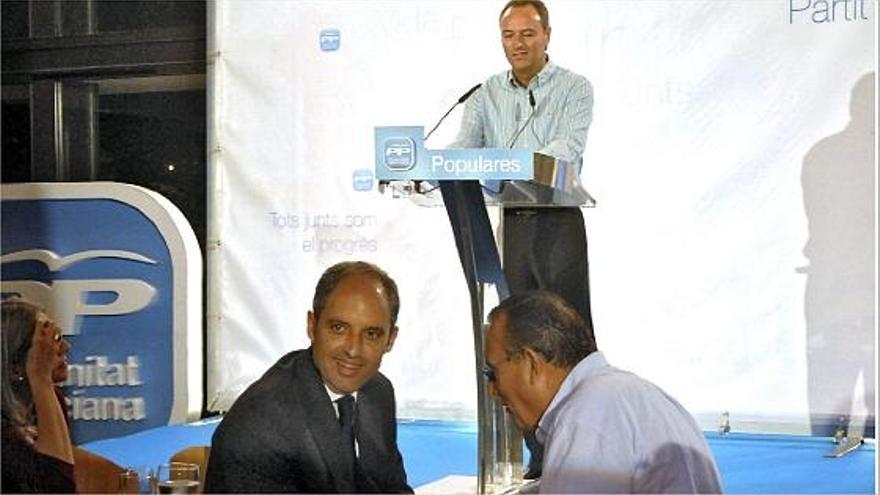 Carlos Fabra y Francisco Camps conversan mientras Alberto Fabra interviene en un mitin del PP.