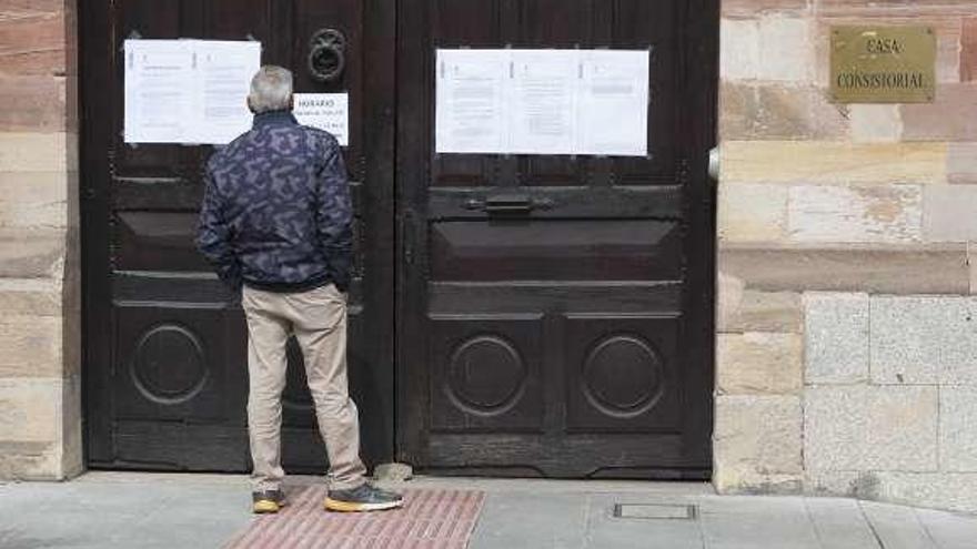 Un vecino lee avisos en la Casa Consistorial de la plaza del Grano.