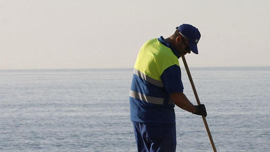 Un empleado trabajando en la limpieza de la playa.