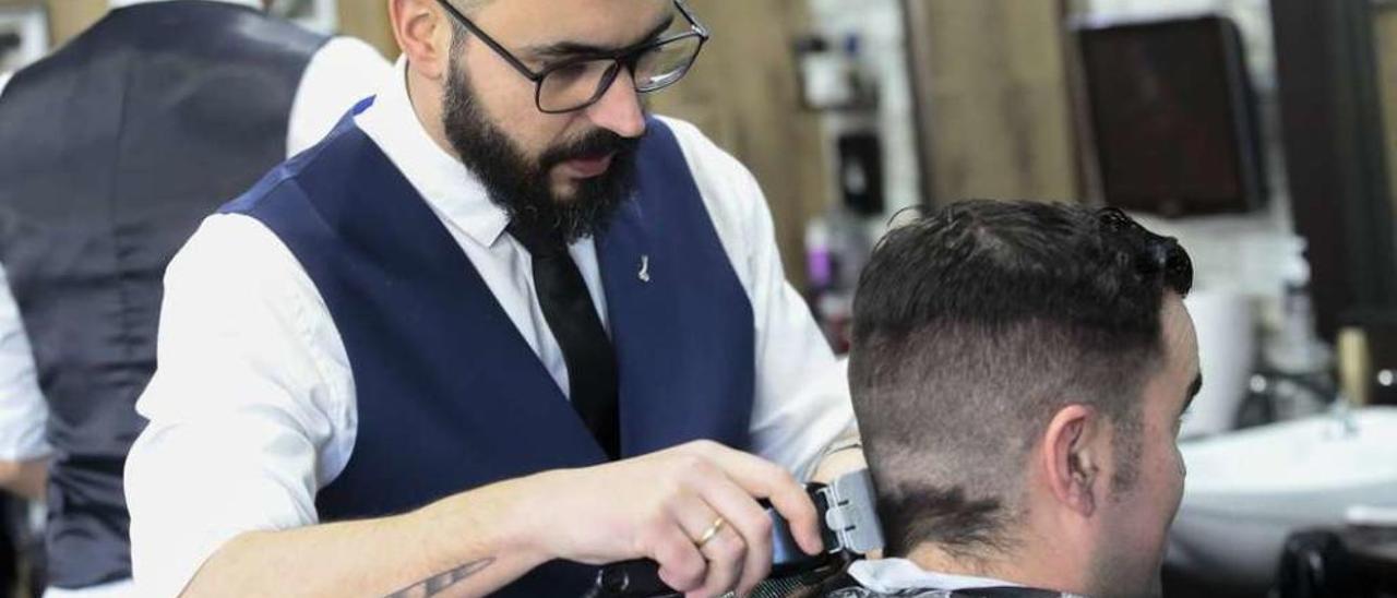 Juan Roch realiza un corte de pelo a un cliente en su barbería de la calle Barcelona. // Adrián Irago