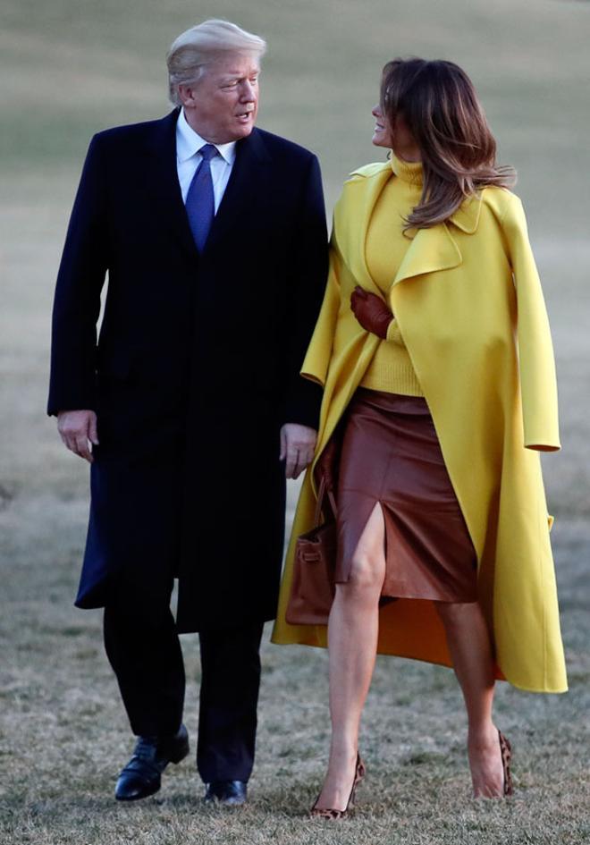 Melania Trump con jersey, abrigo amarillo y falda de piel junto a Donald Trump