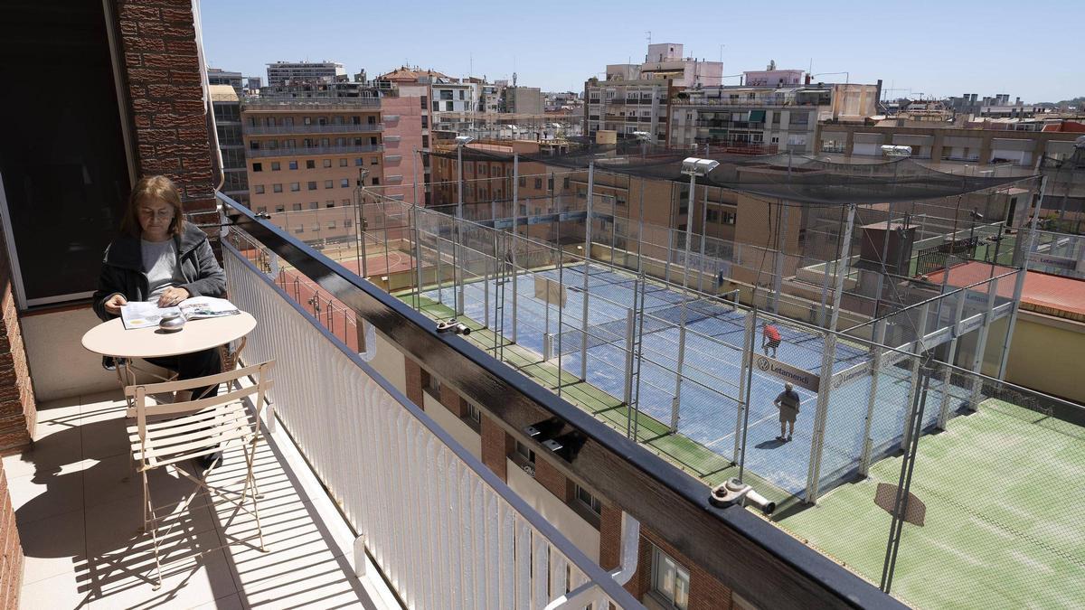 Una vecina en el balcón de su piso de Barcelona, frente a una de las pistas de pádel del terrado del colegio Pare Manyanet de Les Corts.