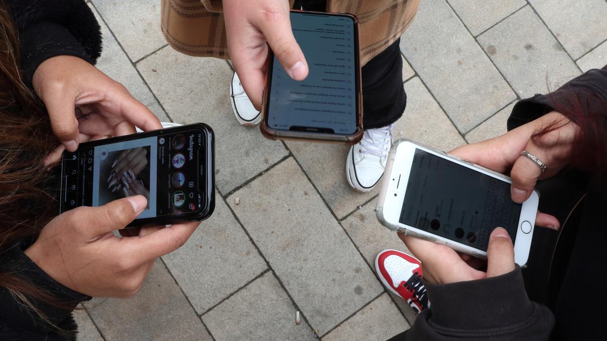 Varios jóvenes utilizando teléfonos móviles.