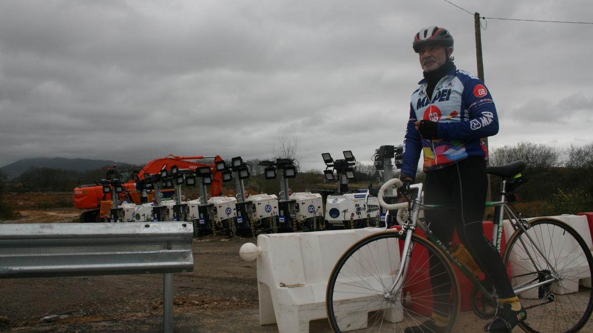 Juan Tomás Serrano, con su bici, en Bobes, ante una de las zonas donde hay depositada maquinaria.