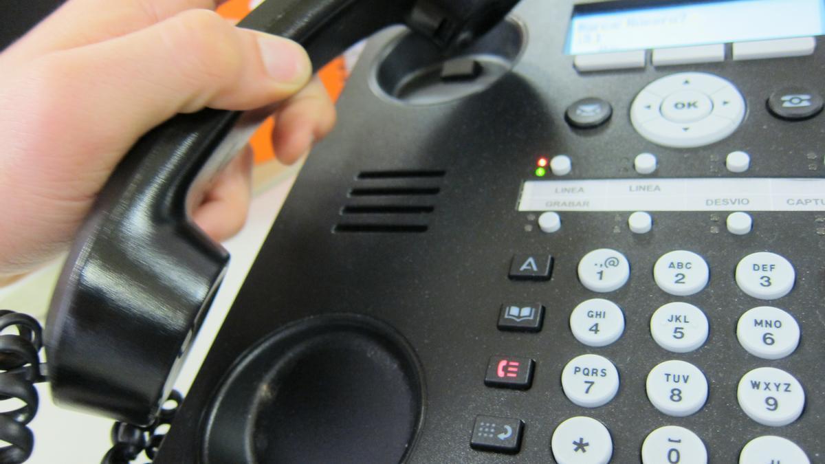 Un hombre coge un teléfono fijo en su casa.