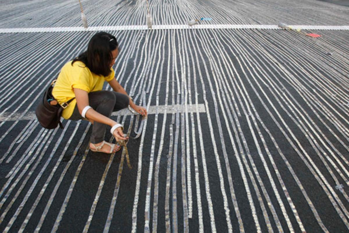 Una voluntària participa en l’intent d’aconseguir un rècord Guiness alineant el màxim de monedes en un parc de Manila (Filipines).