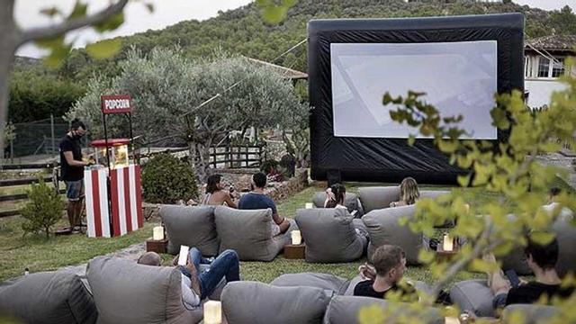 Vista del jardín de una finca ubicada en la Serra con la instalación de la pantalla y los 'puffs' sobre el césped.