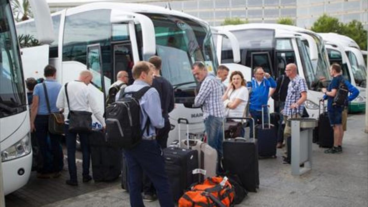 Un grupo de turistas esperan en el aeropuerto de Palma a que  los autobuses los lleven a sus hoteles.