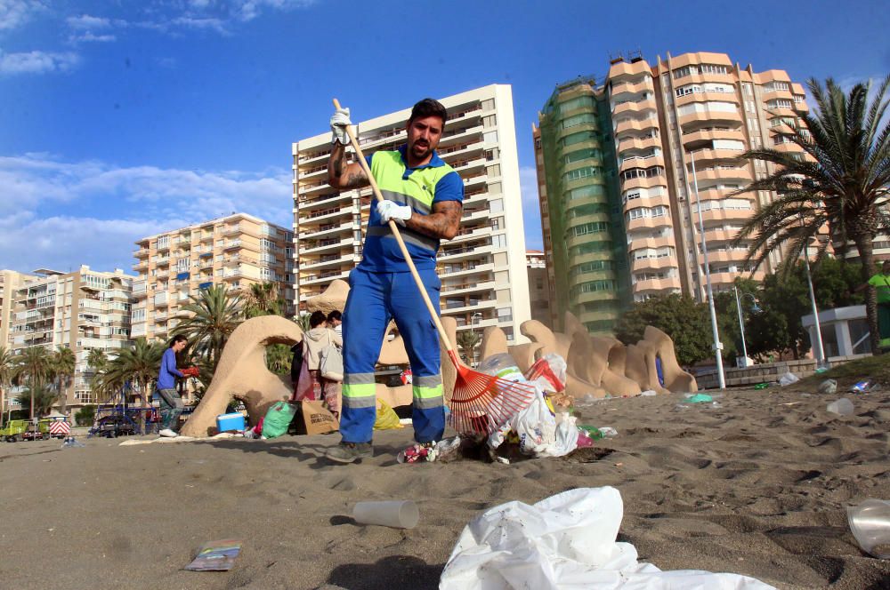 Los operarios de los servicios de limpieza trabajan para dejar la playa en óptimas condiciones tras una larga noche de fiesta en la arena