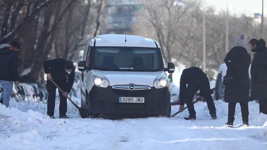 Vecinos de un barrio de Madrid ayudan a un conductor a sacar su coche.