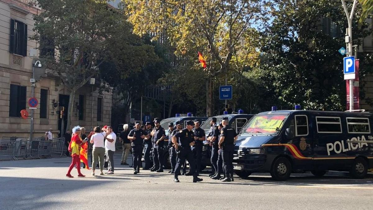 Varias personas saludan a unos agentes de la Policía Nacional, en Barcelona.