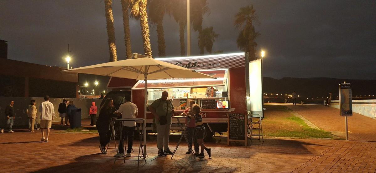 El food truck A puro grill atendiendo a un grupo de clientes en las inmediaciones del parque de la Música.