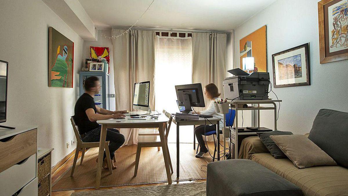 Dos personas teletrabajan desde el salón de su casa.