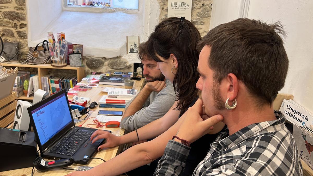 Una de les impulsores de la Traça Cultural, la gestora cultural Maria Giró, mostrant la plataforma web a dos socis treballadors de la llibreria El Refugi de la Seu d'Urgell, Pol Maese i Miquel Albero