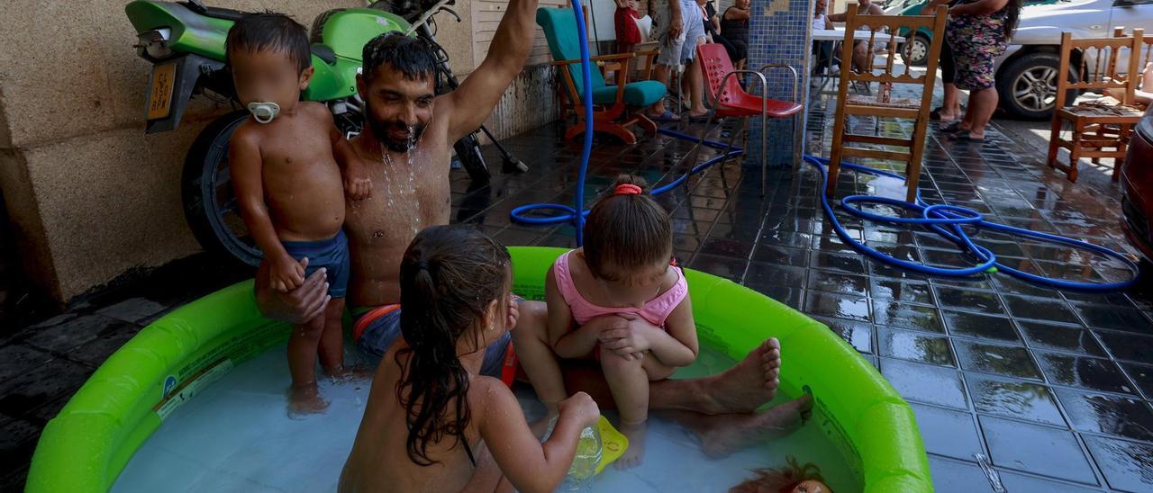 Varios niños con su padre en un barrio empobrecido de València, durante la ola de calor de este verano.