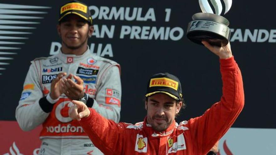 Fernando Alonso celebra su tercer puesto en el podio del circuito de Monza con Hamilton detrás. / luca zennaro / efe
