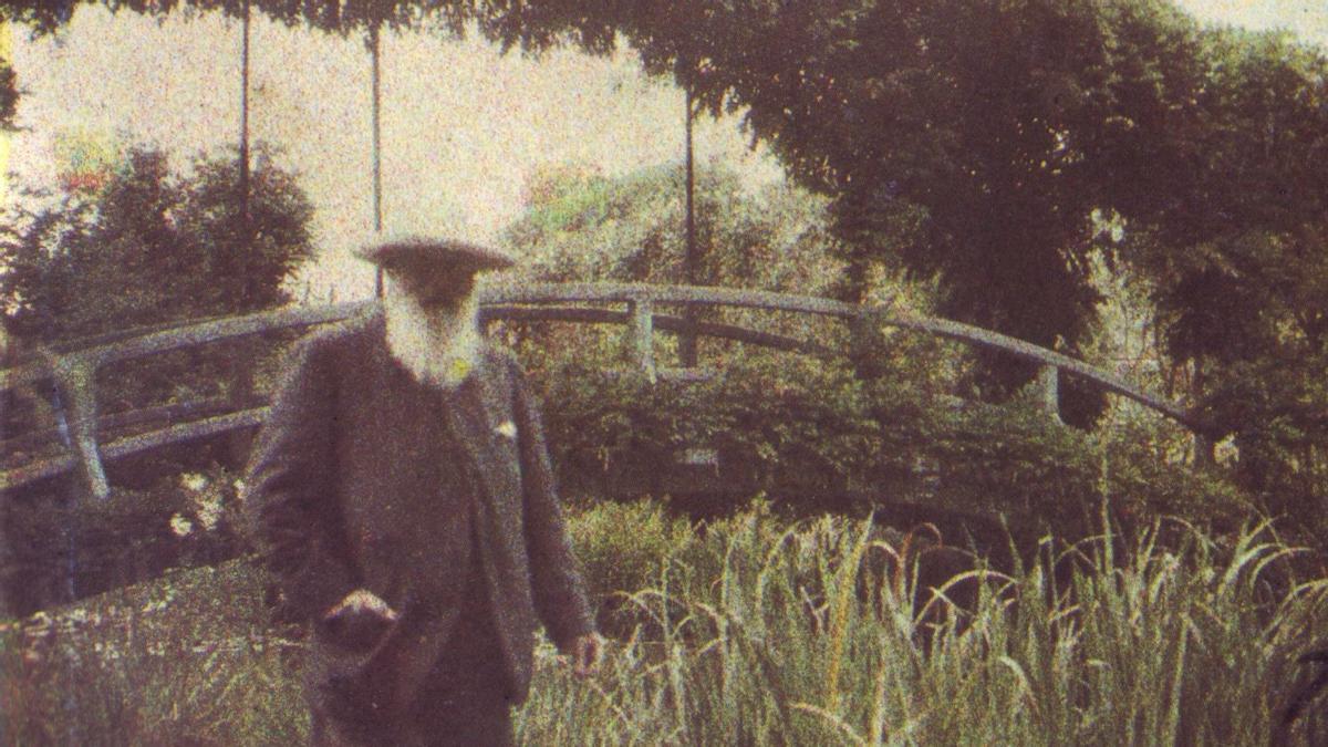 Claude Monet, ya anciano, en el jardín de Giverny, con el célebre puente japonés al fondo.