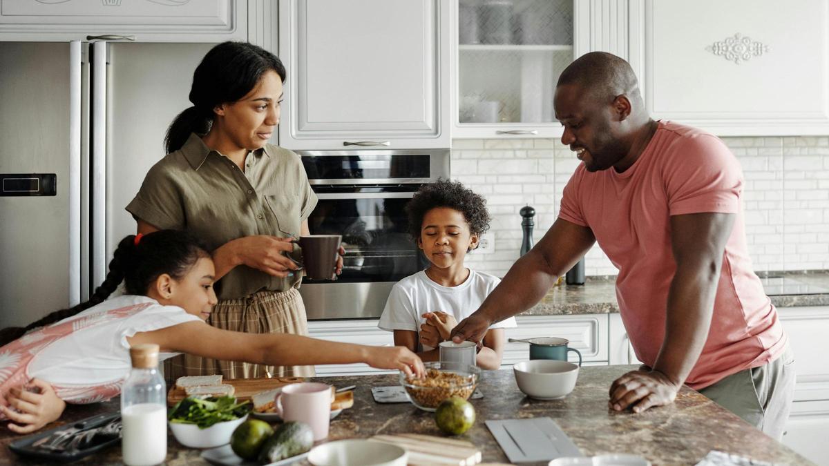 Unos padres en la cocina junto a sus dos hijos.