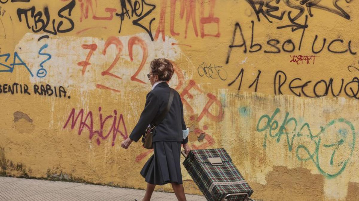 Una mujer pasea entre pintadas en la calle Postigo Bajo. | Irma Collín