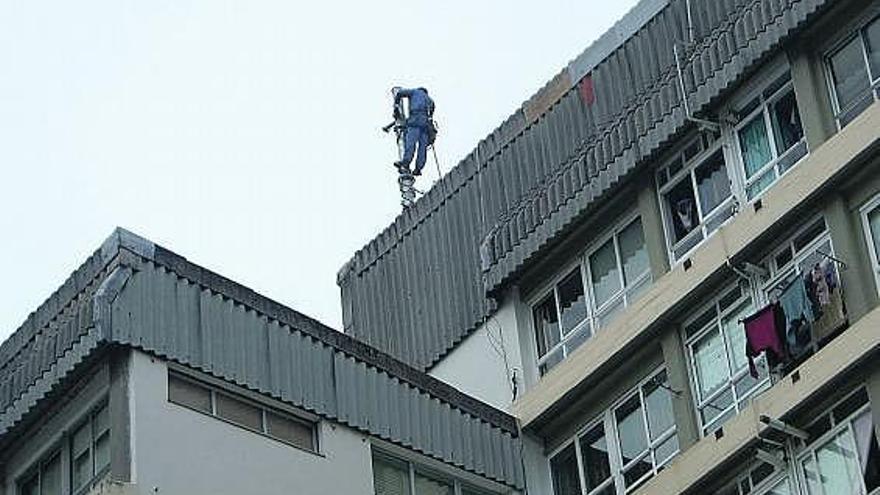 Un operario instala la antena en el tejado del edificio. / la opinión