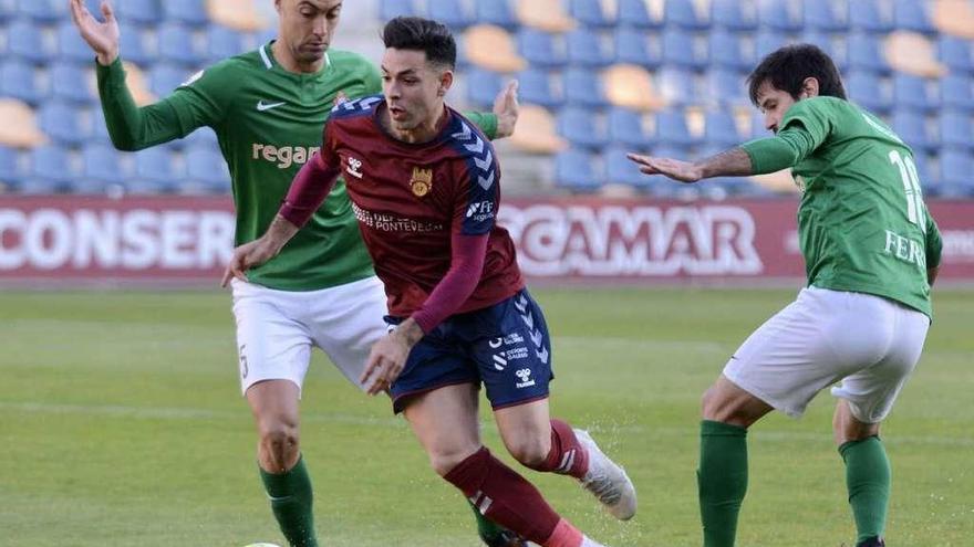 Álvaro Bustos supera a dos rivales del Racing de Ferrol en el último derbi disputado en Pasarón. // Rafa Vázquez