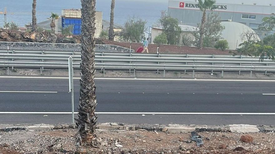 Un hombre cruza la TF-1 junto a una maleta mientras circulan vehículos