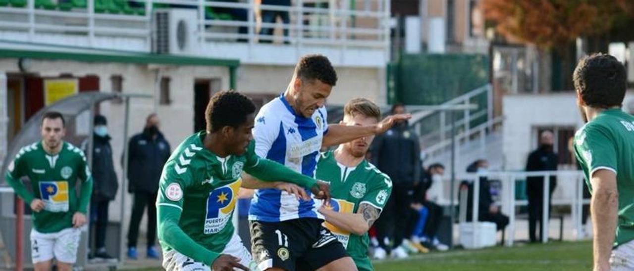 Tano, rodeado por dos jugadores del Marchamalo, protege el balón.